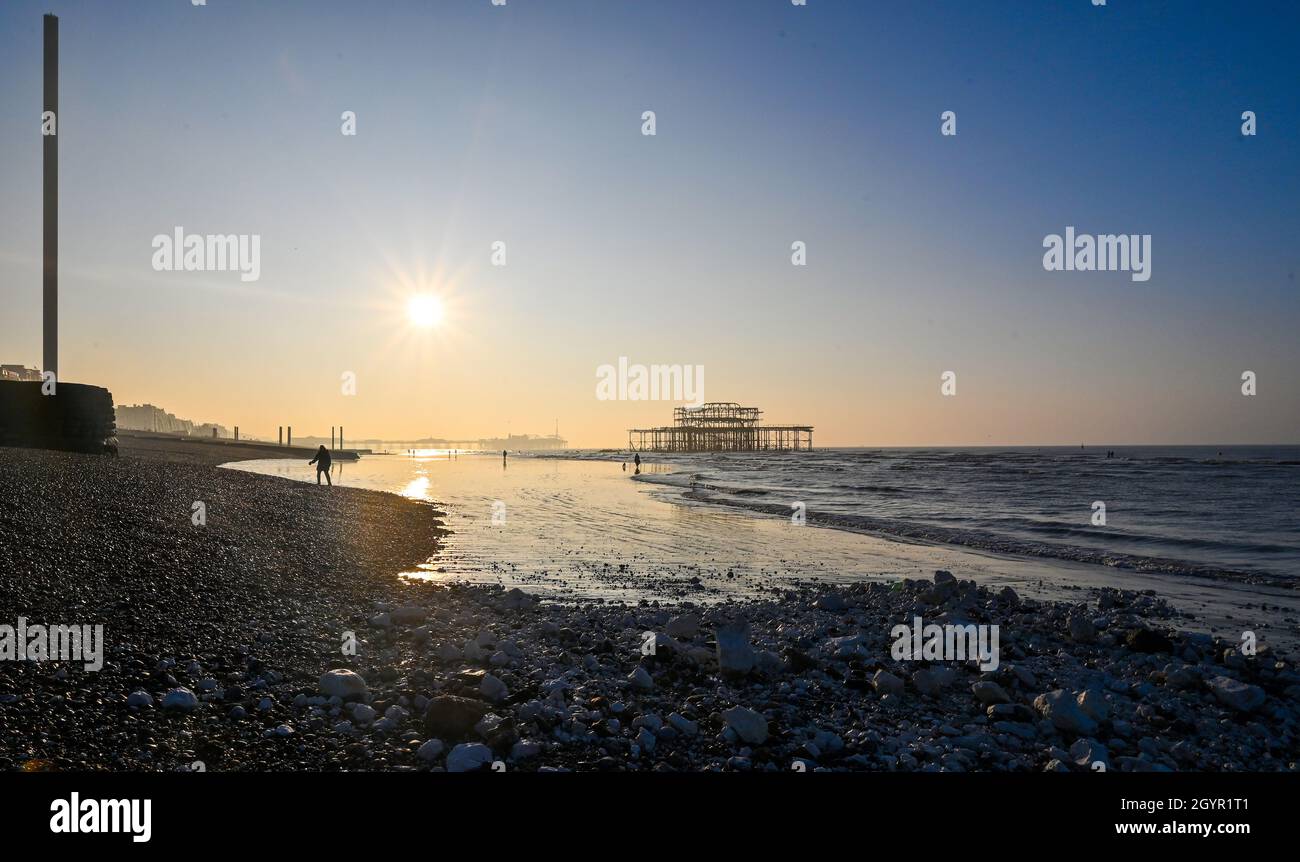 Brighton UK 9th October 2021 - Walkers enjoy a beautiful morning and an extra low tide on Brighton beach as warm sunny weather is forecast for parts of the UK today : Credit Simon Dack / Alamy Live News Stock Photo