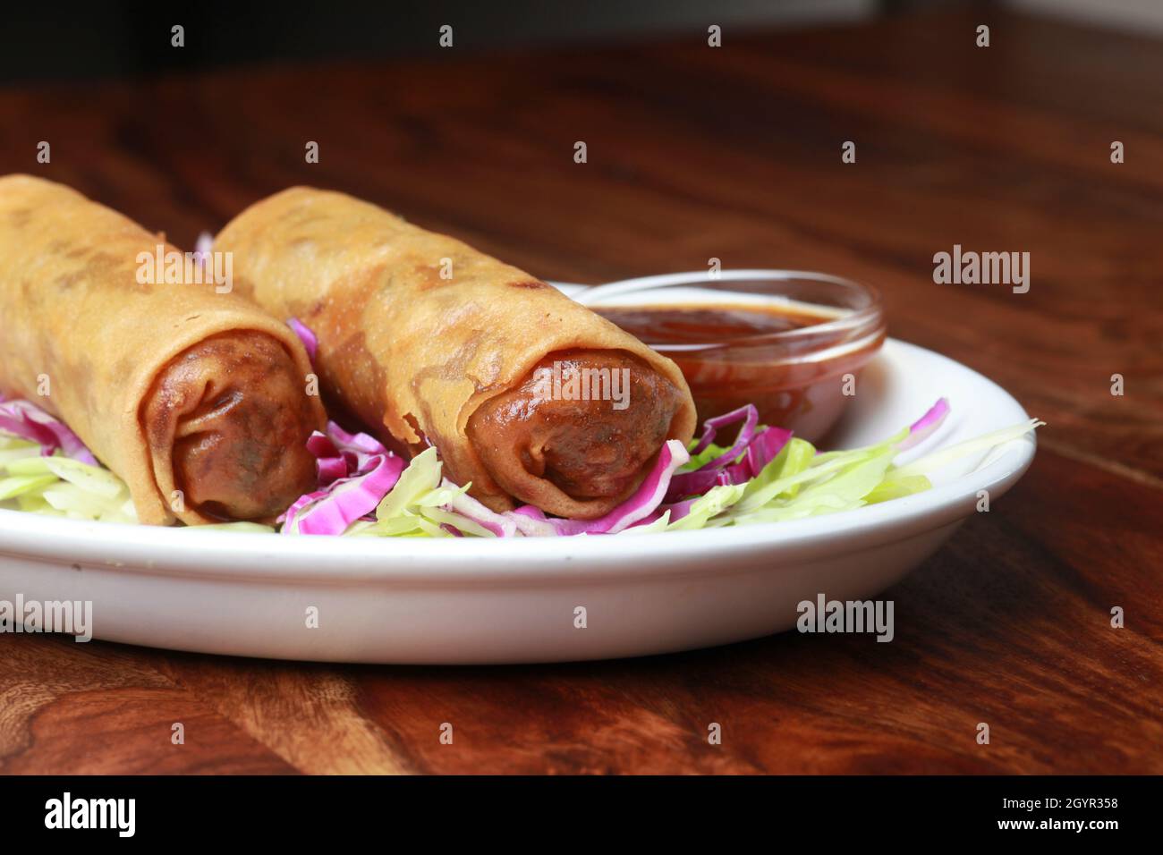 Two Egg rolls in a plate Stock Photo