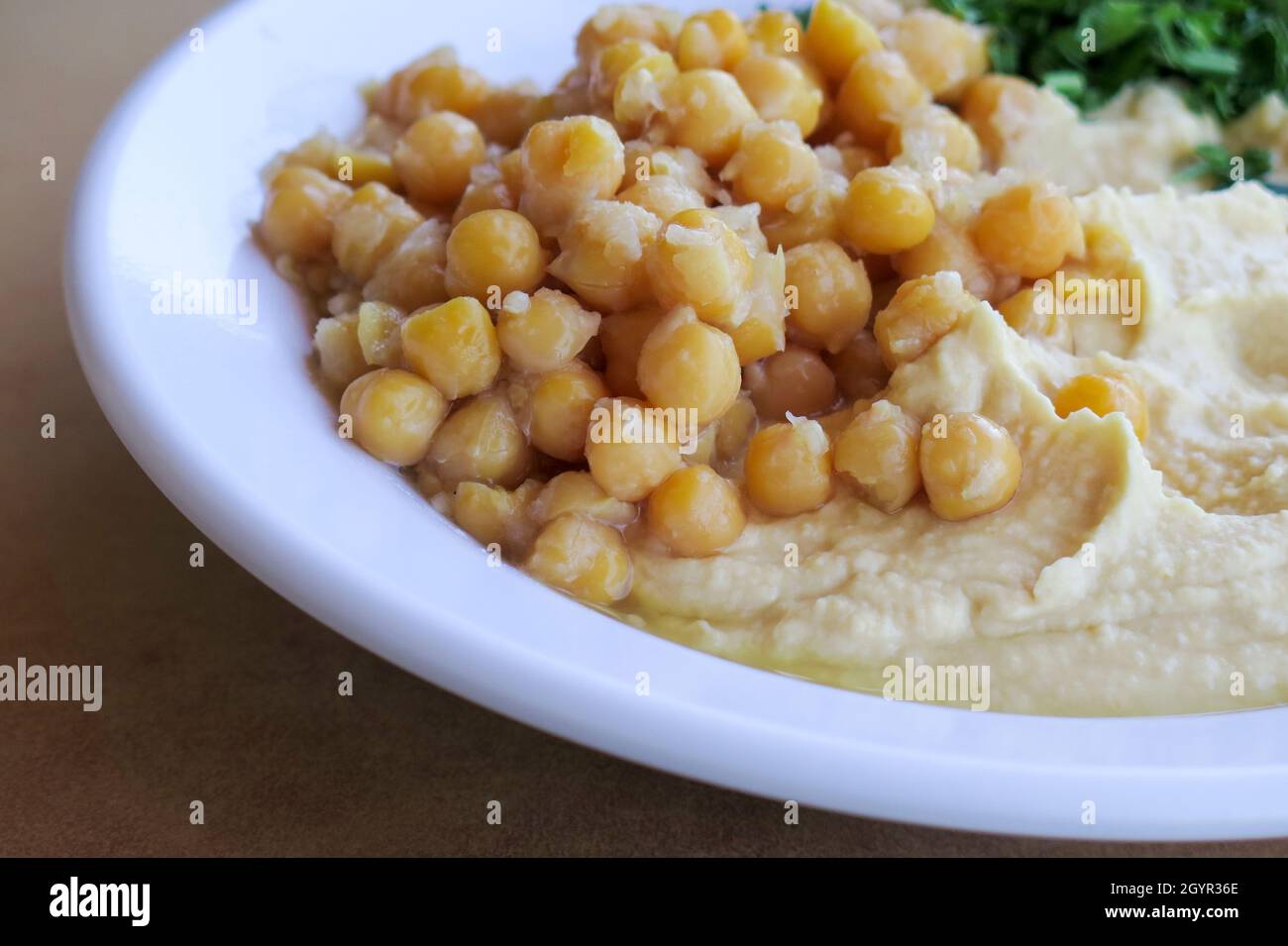 Hummus. A Levantine Arab dip or spread made from cooked, mashed chickpeas, blended with tahini, olive oil, lemon juice, salt and garlic. Garnished wit Stock Photo