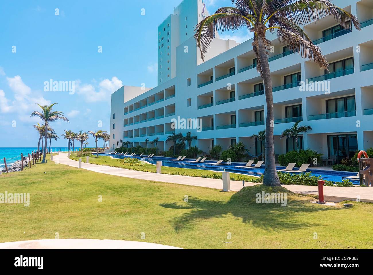 View of luxury hotel and empty swimming pool with deck chair by sea ...