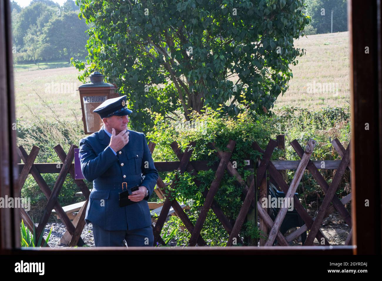 Sheringham, Norfolk, UK - SEPTEMBER 14 2019: Man in 1940s RAF officer uniform holds his chin viewed from inside steam train carriage at Weybourne Stock Photo