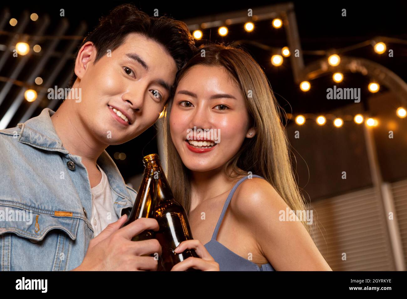 happy asian teenager couple man and woman in love drinking beer alcohol and toasting bottle in celebration party. young happy couple love and romantic Stock Photo