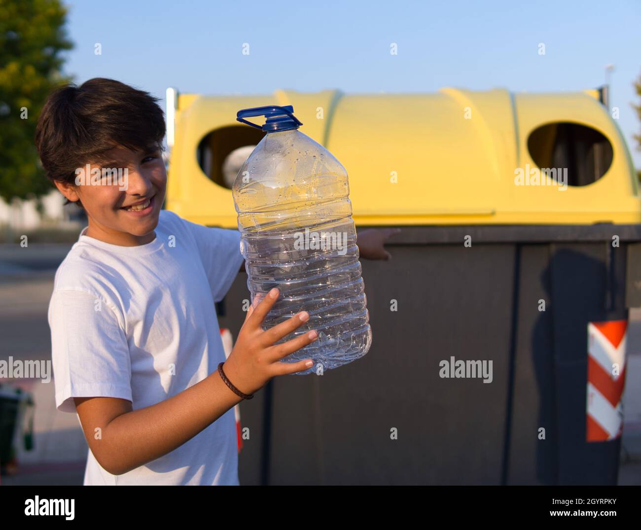 Young boy throwing a plastic bottle into the recycle bin Stock Photo