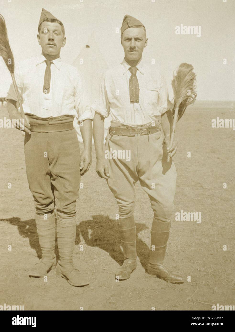 Two First World War era Britsh army officers wearing side caps and holding fly swats. A bell tent can be seen behind them. Stock Photo