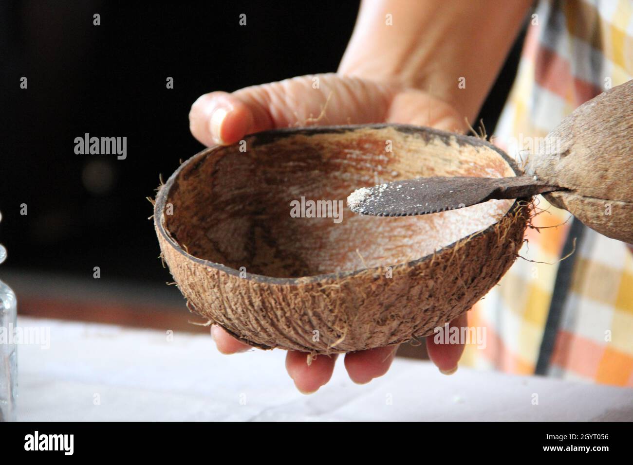 Person adding sugar in a coconut bowl Stock Photo