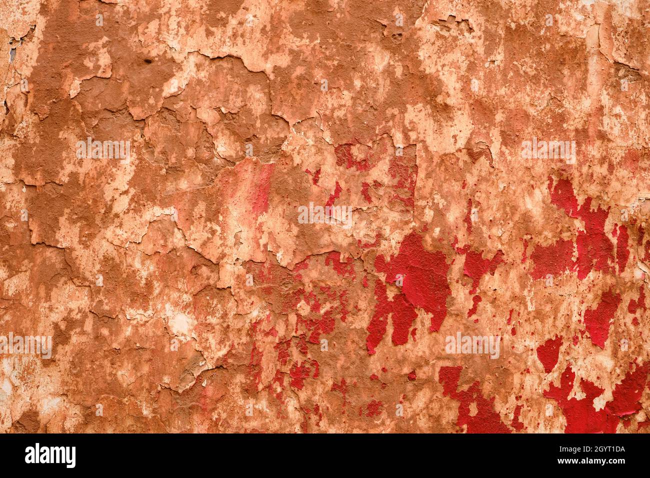 Old ruin wall with red peeling paint, grunge background or texture