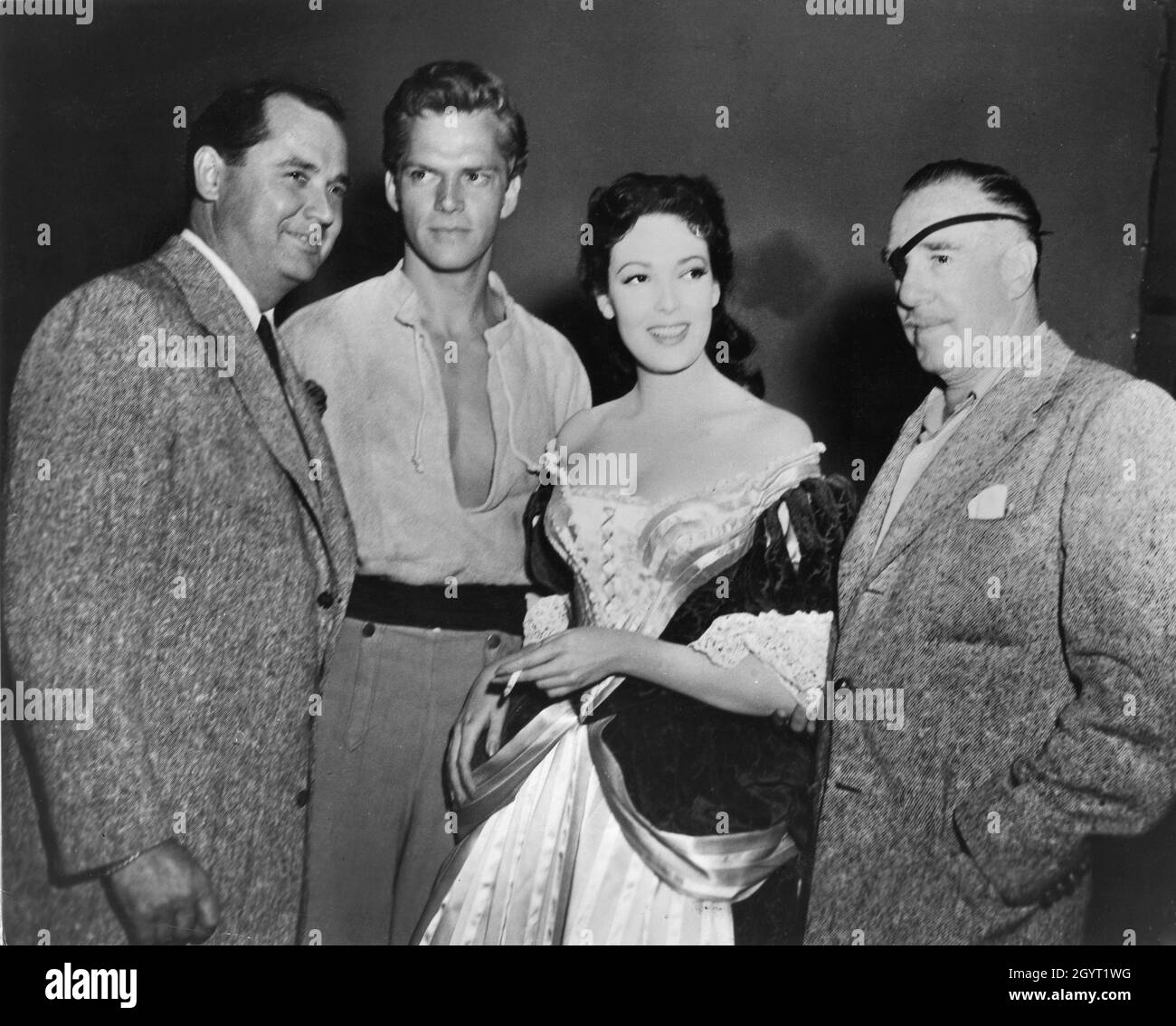 Producer EDMUND GRAINGER KEITH ANDES LINDA DARNELL and Director RAOUL WALSH on set candid during filming of BLACKBEARD THE PIRATE 1952 director RAOUL WALSH story DeVallon Scott screenplay Alan Le May costume design Michael Woulfe music Victor Young producer Edmund Grainger RKO Radio Pictures Stock Photo