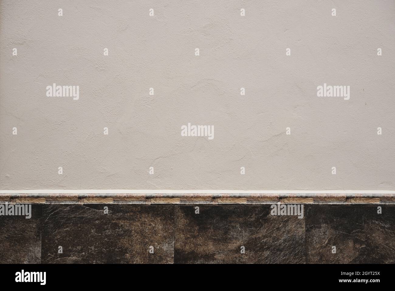 White limewash plaster wall with stone finish ceramic tile skirting