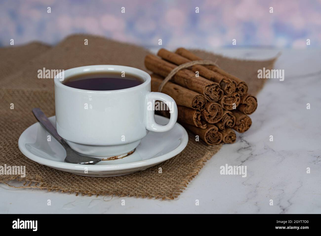 A cup of tea with a stack of cinnamon sticks on the side. Selective focus points. Blurred background Stock Photo