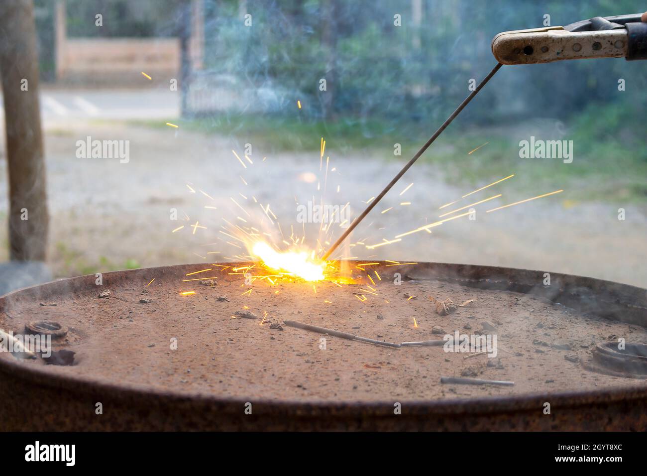 A young welder is Welding a steel fuel tank with blue sparks fly in a