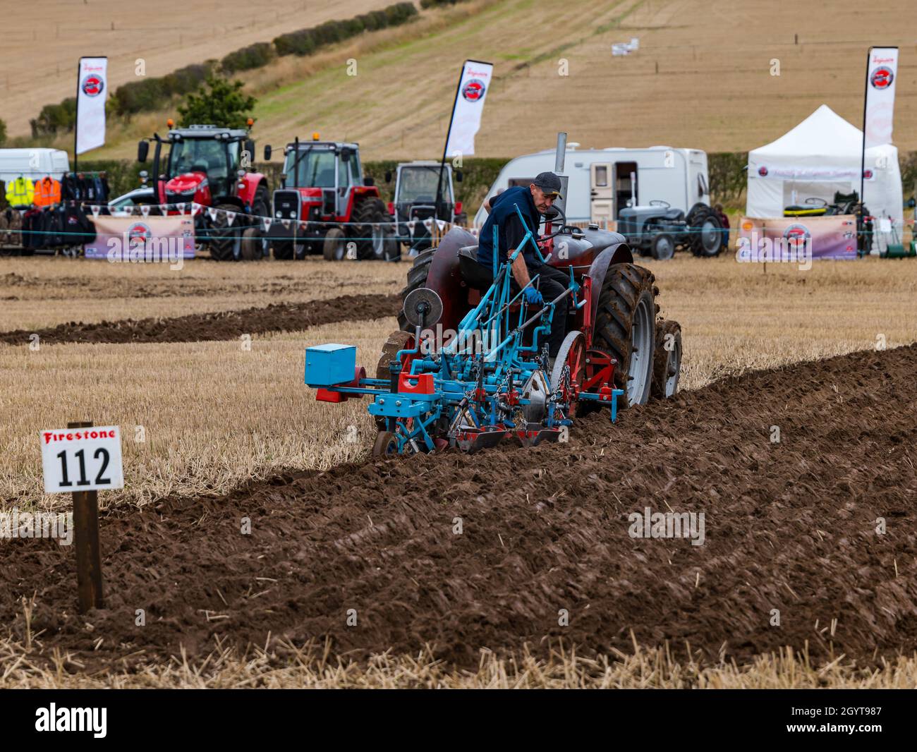 Mindrum Mill, Northumberland, UK. 09 October 2021. British Ploughing Championships: the 70th championships, cancelled due to Covid-19 last year, take place. A variety of tractor classes and ploughs compete for prizes over the two day event. Pictured: the oat seed furrow ploughing by tractor. Stock Photo