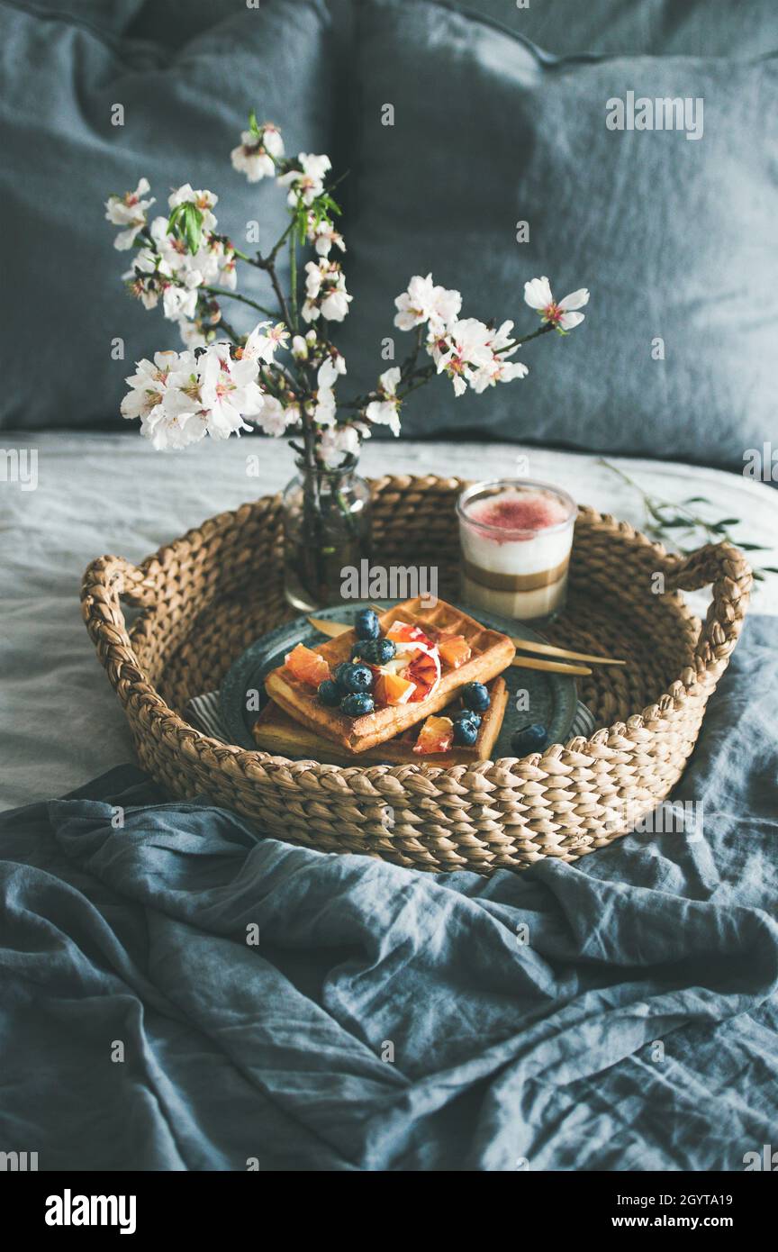 Waffles with blood orange and blueberries, rose latte in glass and blooming flower Stock Photo