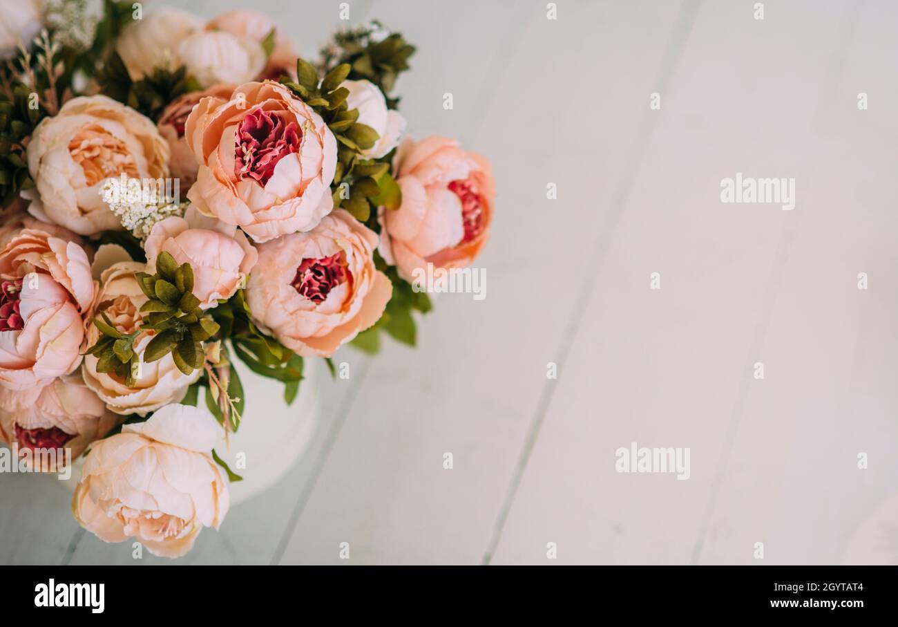 beautiful beige flower bouquet with green leaves on the light wooden flloor Stock Photo