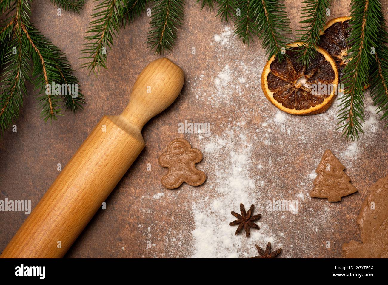 Gingerbread man cookies and Christmas tree cookies, cut of raw gingerbread dough. The work surface is sprinkled with flour. Stock Photo