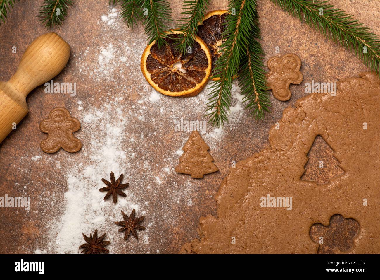 The kitchen worktop is sprinkled with flour. Gingerbread dough is rolled out with a rolling pin. Start making gingerbread cookies! Stock Photo