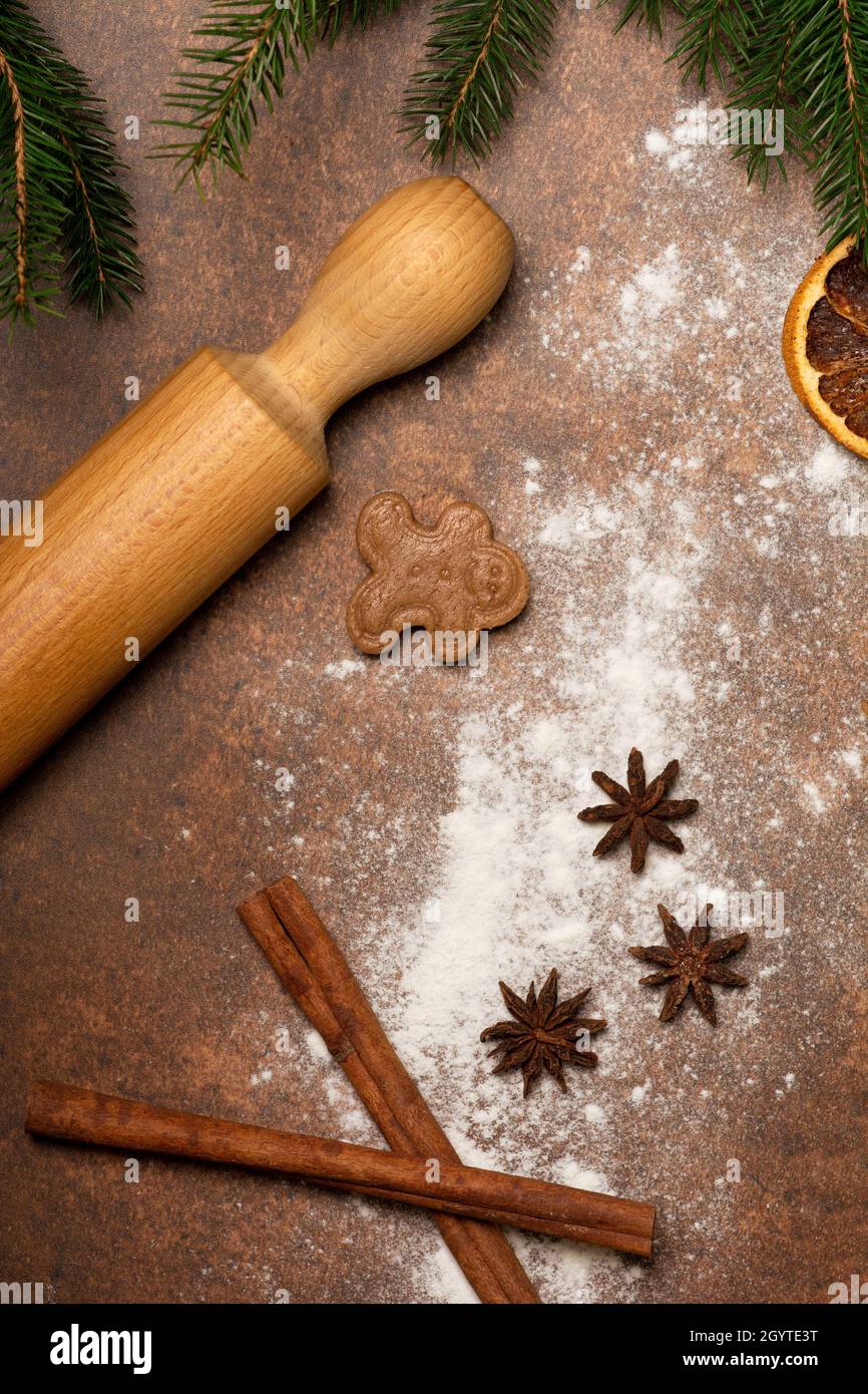 Holiday treats. The kitchen worktop is sprinkled with flour. A gingerbread man cookie is lying on the work surface next to a rolling pin and spices. Stock Photo