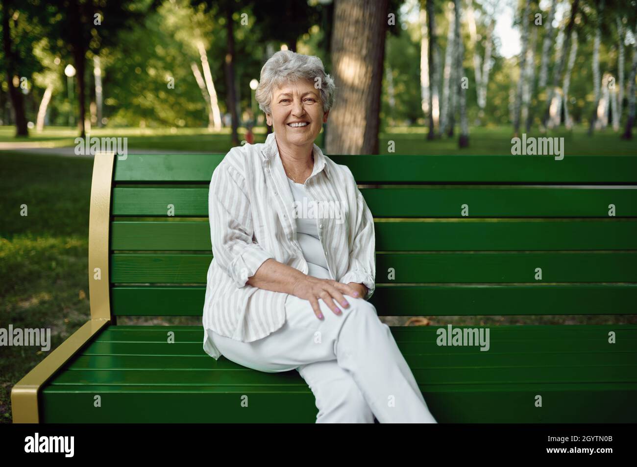 An elderly woman sitting on bench in summer park Stock Photo Alamy