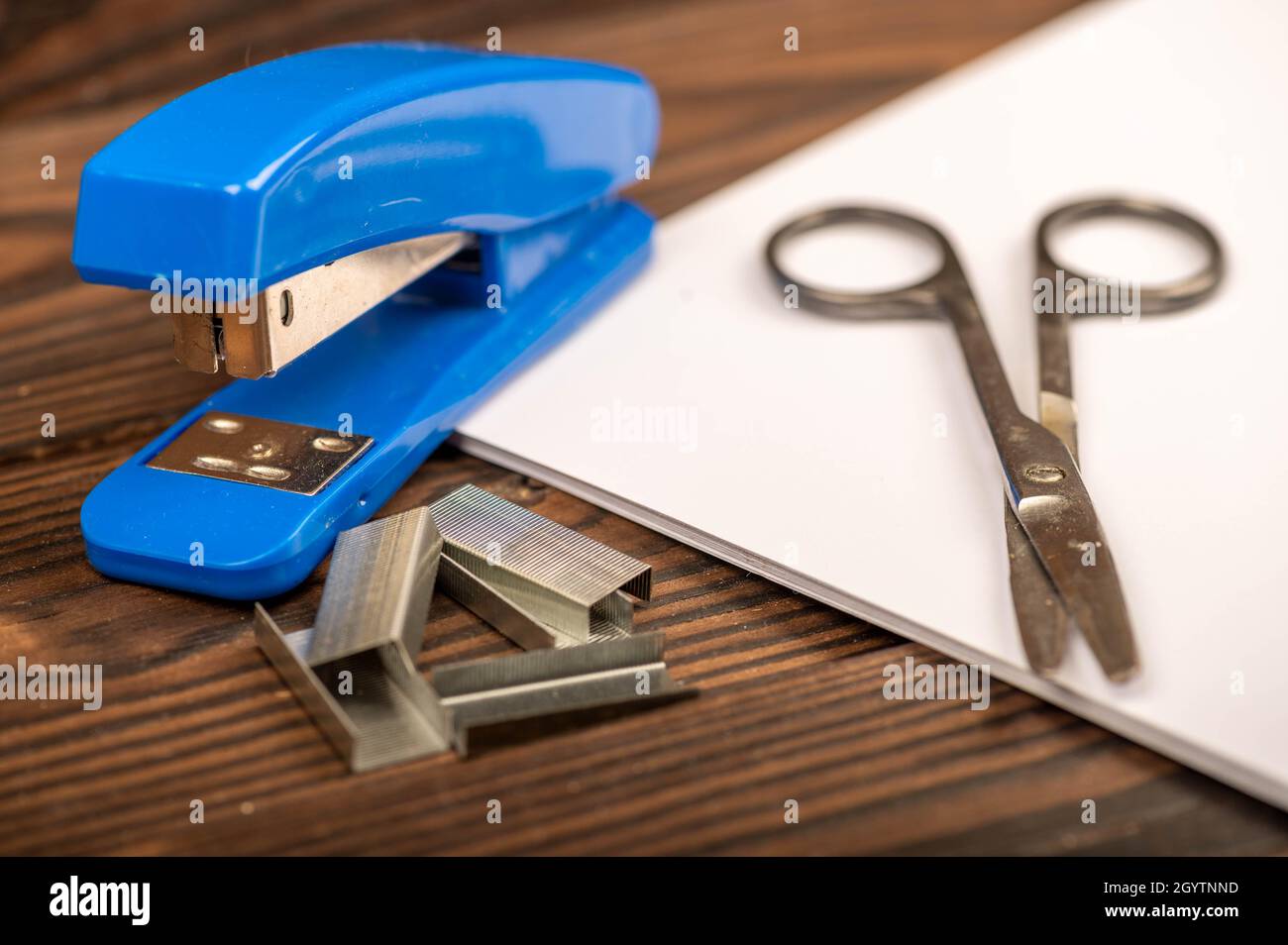 Office stapler, stapler staples and white paper on the table, close-up, selective focus Stock Photo