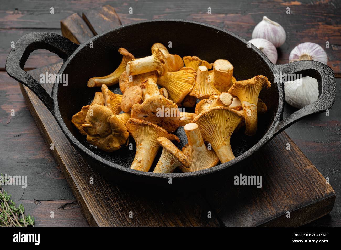 Raw wild chanterelles mushrooms set, in cast iron frying pan, on old