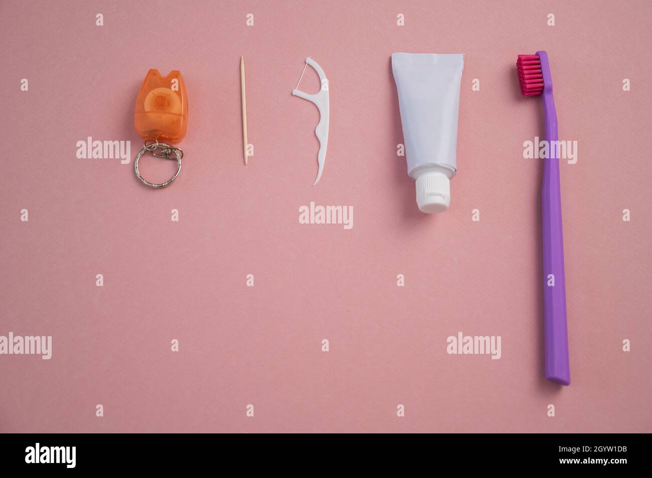 Oral hygiene products on a pink background. Toothbrush toothpaste dental floss and toothpick. Copy space. Stock Photo