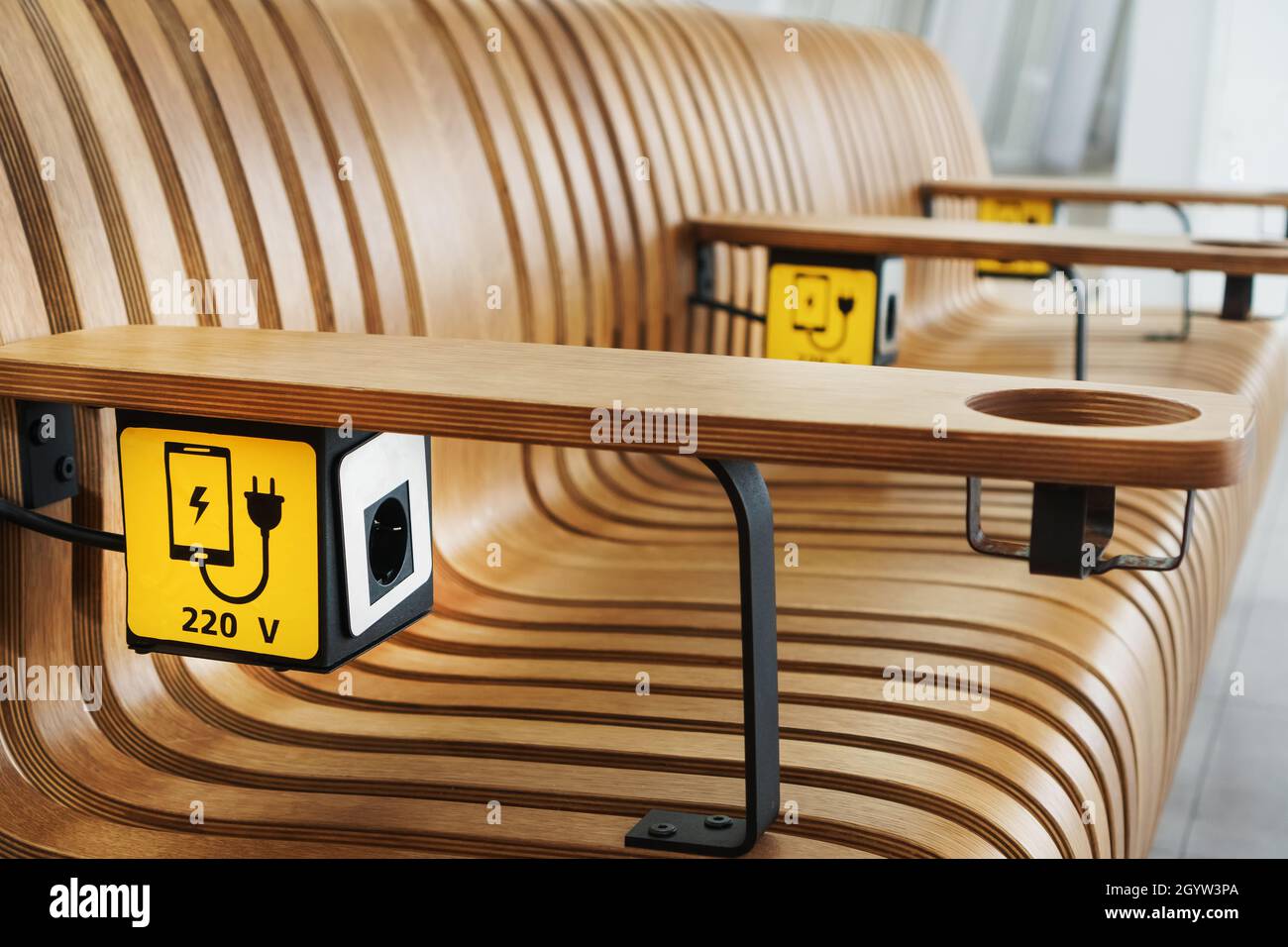 A socket with a device charging sign on a wooden bench at the airport. USB,  Wireless, plug Stock Photo - Alamy