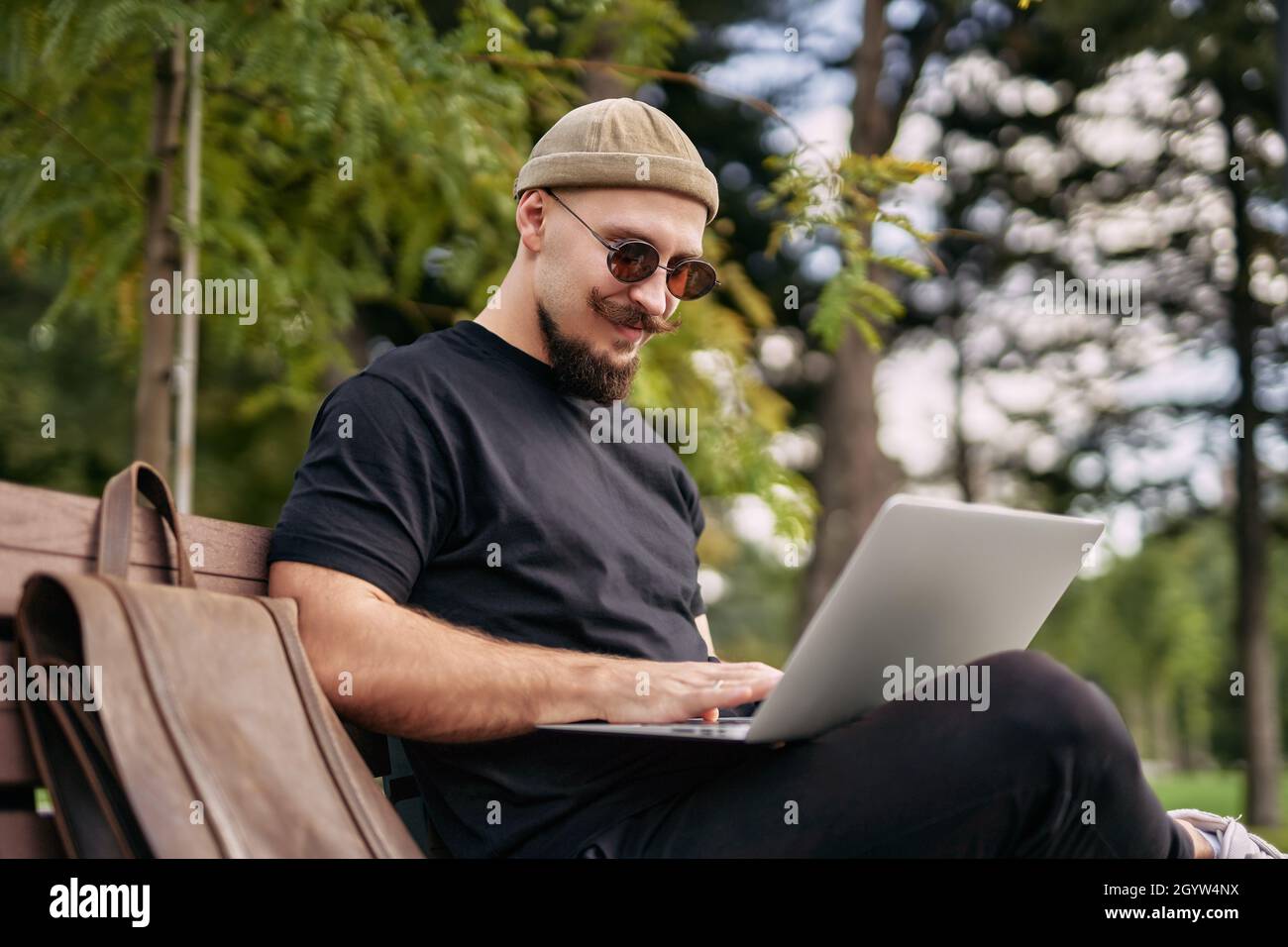 Stylish bearded student chatting working e-learning laptop ps at green park Millennial Hipster  Stock Photo