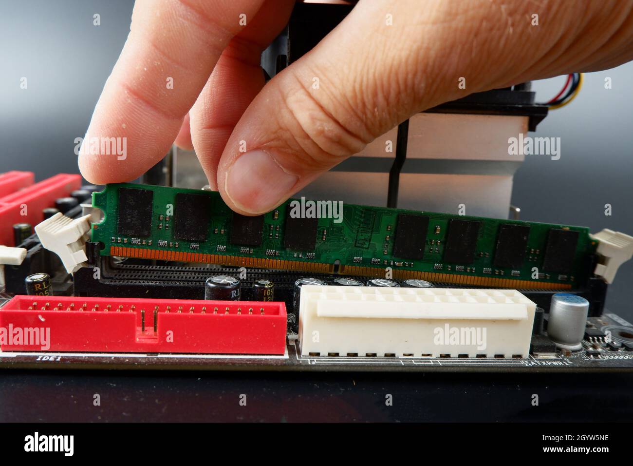 someone installs RAM into a slot on the motherboard of a personal computer. Stock Photo