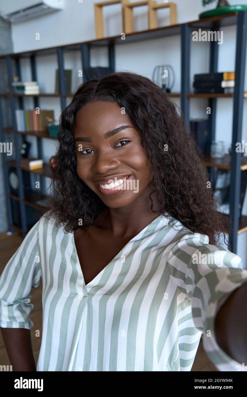 Young happy black African woman holding phone looking at mobile cam streaming. Stock Photo