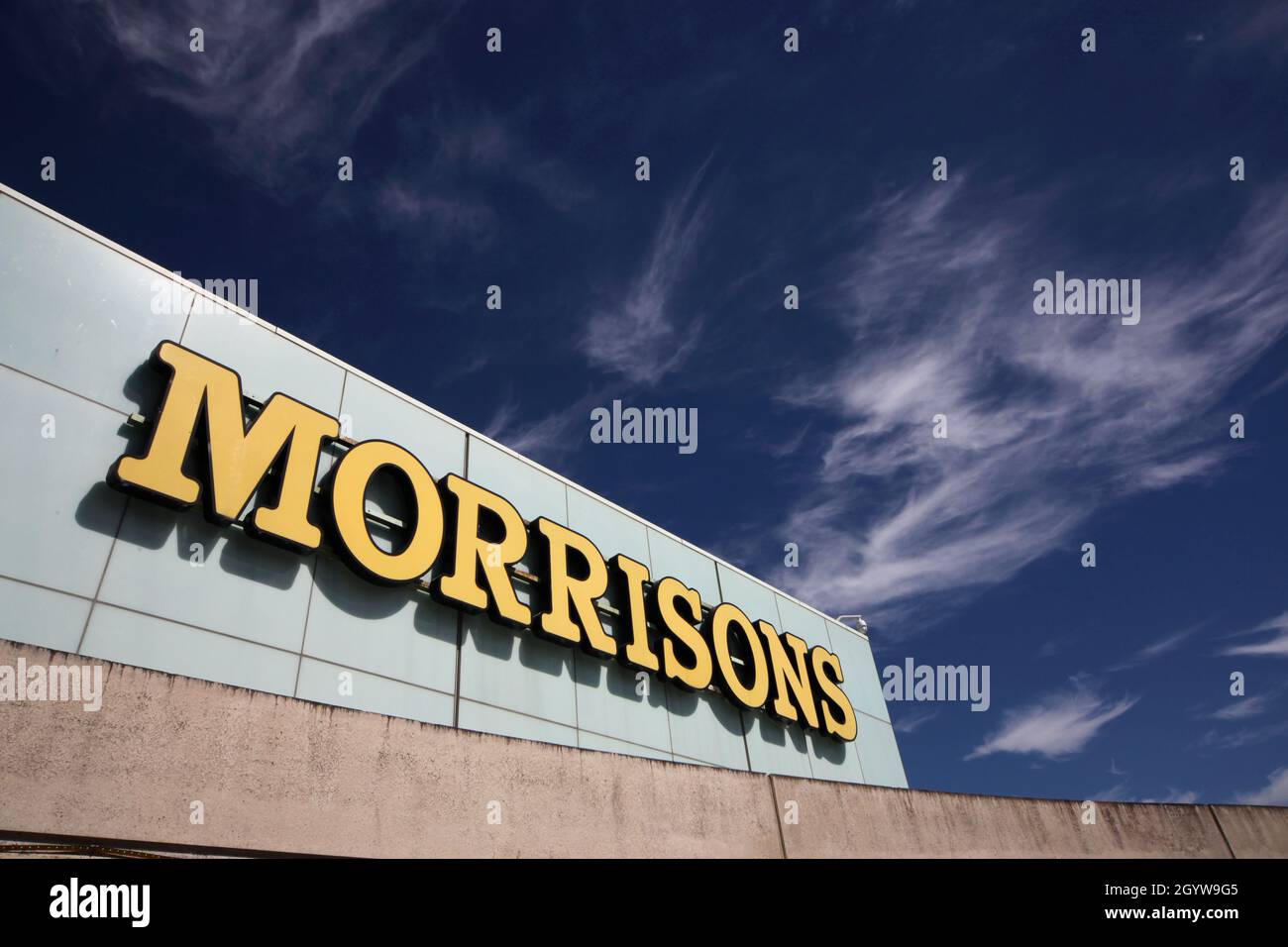 The Morrisons supermarket logo on the side of the Gyle shopping centre in Edinburgh with blue sky and whispy white clouds in the background Stock Photo