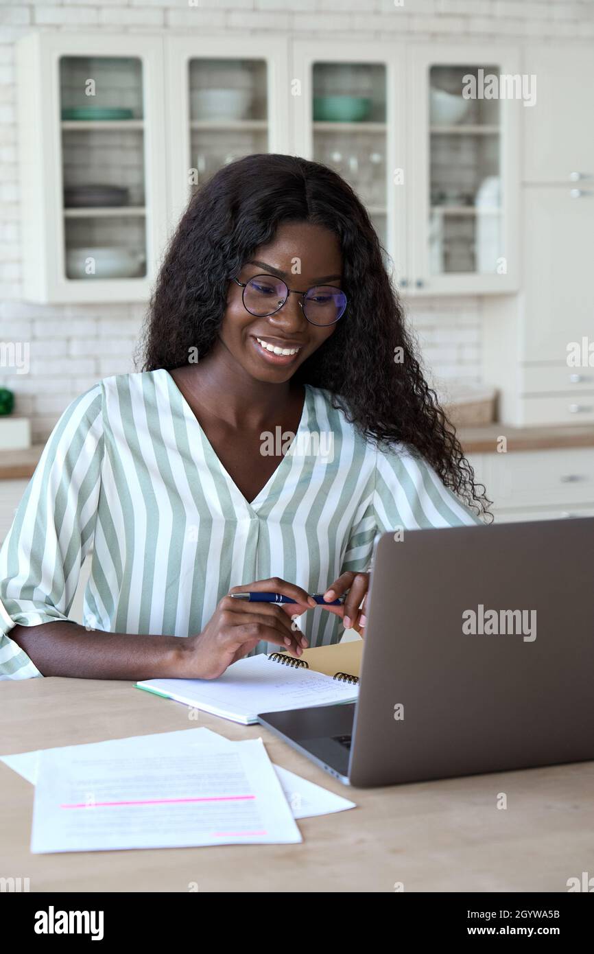 Young happy black woman student learning at home watching webinar. Stock Photo