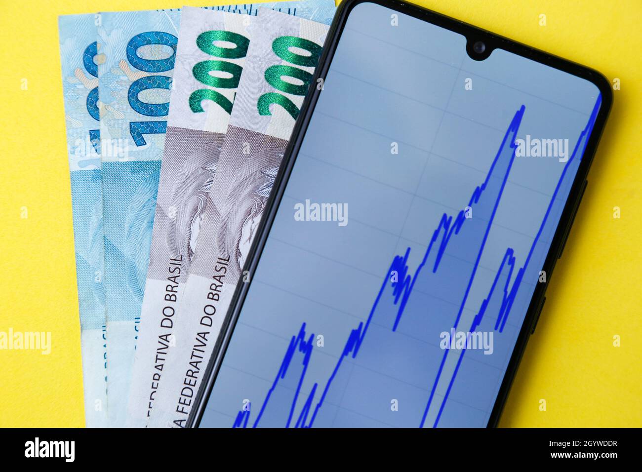 money banknotes and phone screen with financial chart on yellow background Stock Photo