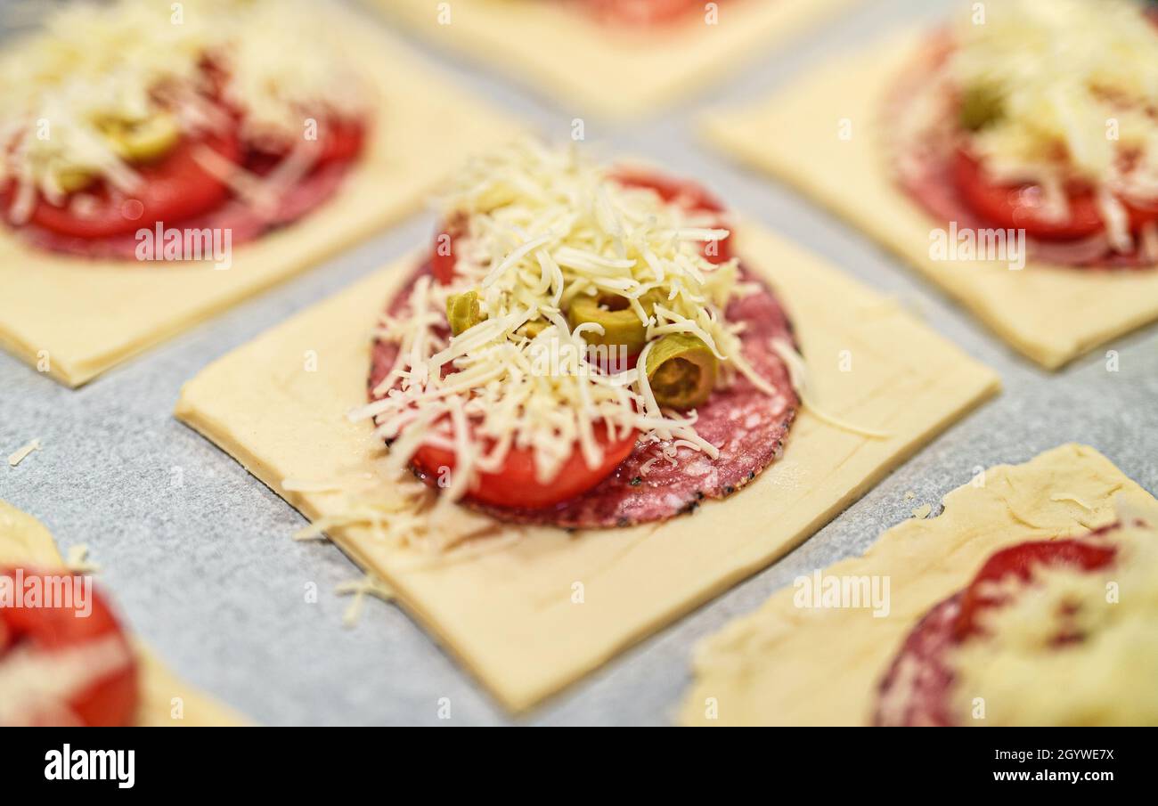 Square mini pizzas with salami, cheese, olives and tomato. Stock Photo