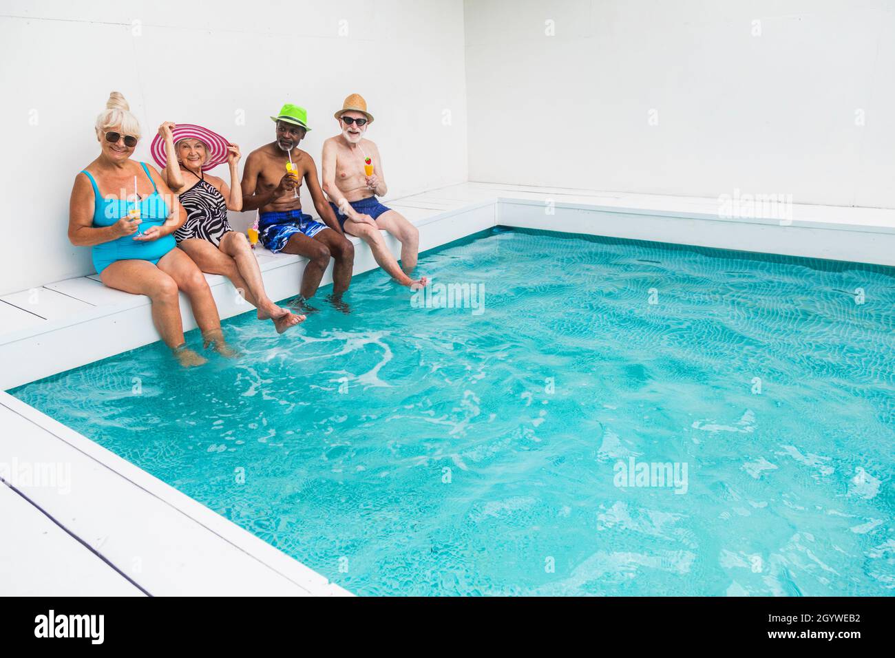 Happy seniors having party in the swimming pool - Elderly friends at a pool party during summertime Stock Photo