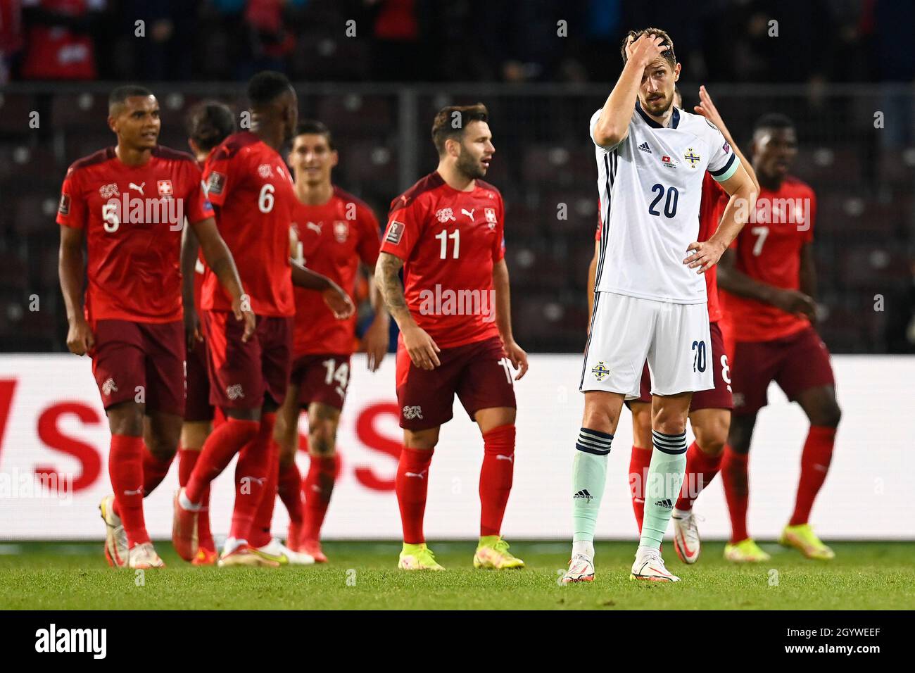 Switzerland’s Steven Zuber celebrates scoring their side's first goal of the game with team-mates as Northern Ireland’s Craig Cathcart stands dejected during the FIFA World Cup Qualifying match at Stade de Geneve, Switzerland. Picture date: Saturday October 9, 2021. Stock Photo