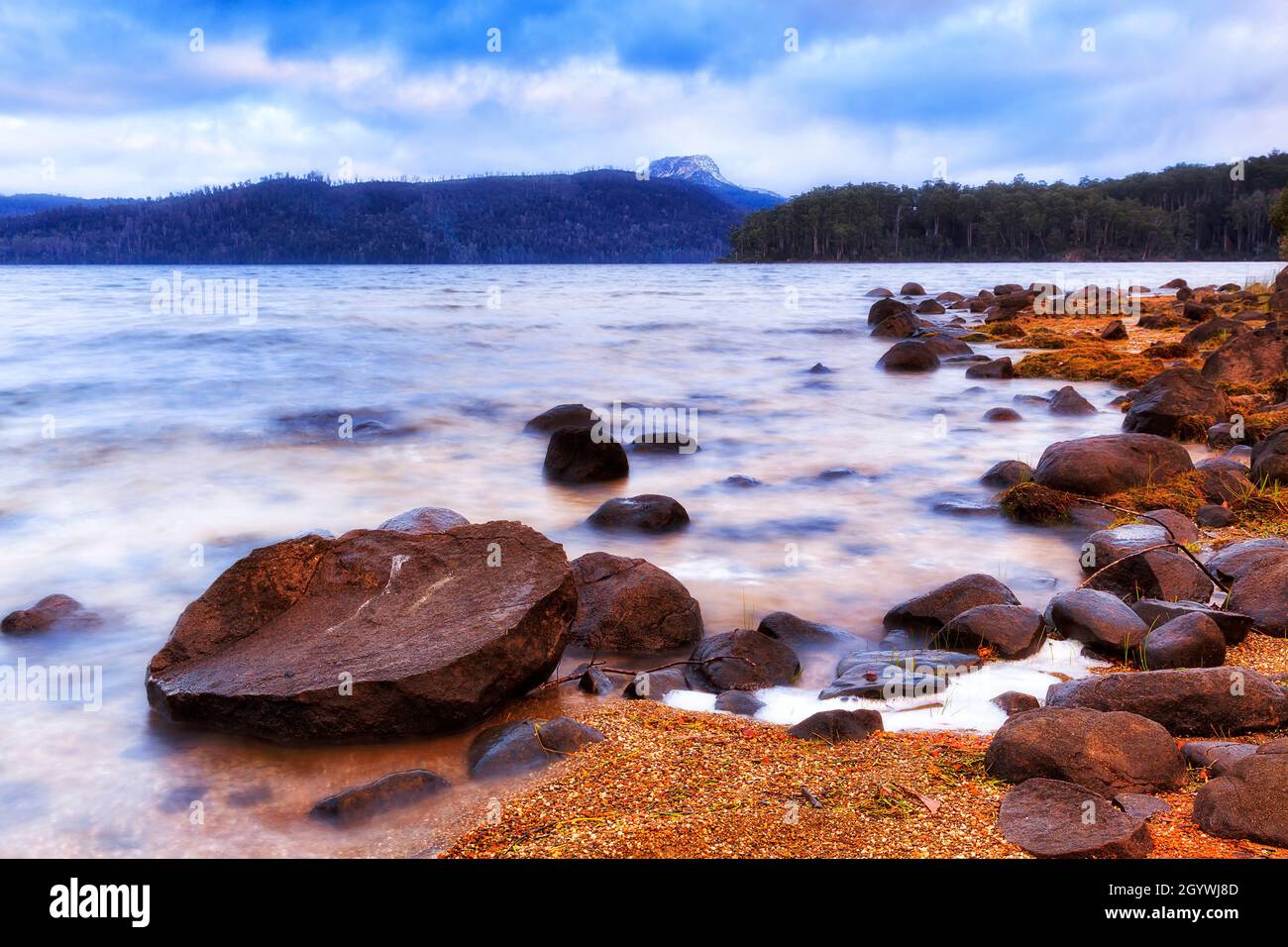 Rock boulders on shores of St Clair lake in Tasmania in vew of distant