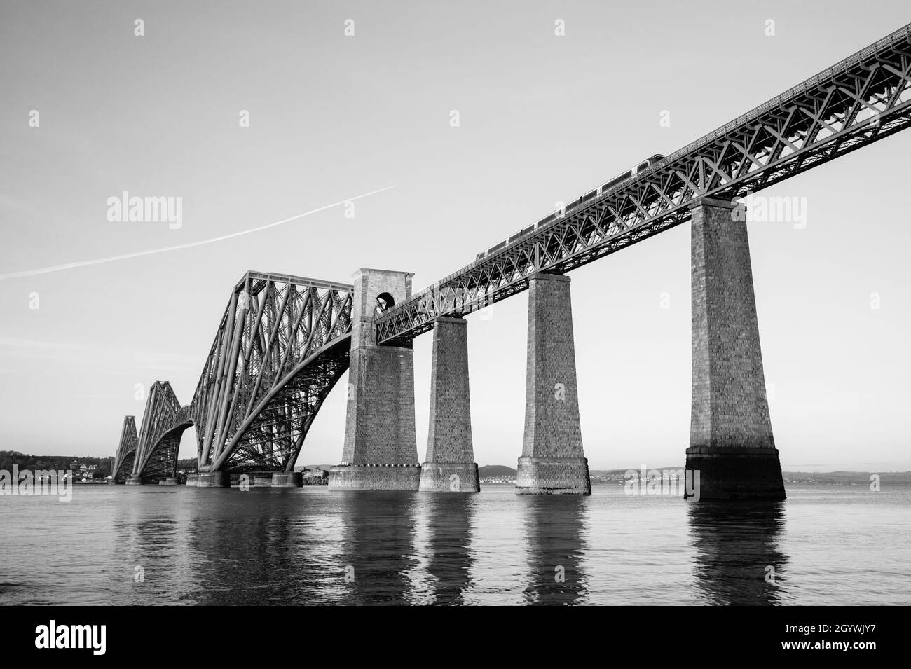 View of the iconic Forth Rail Bridge from South Queensferry quayside with low winter sun near dusk. Stock Photo