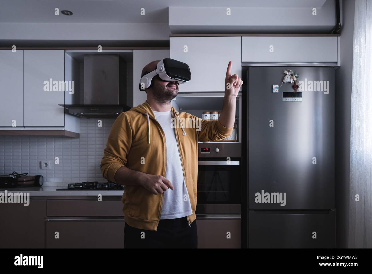 The young man who entered the world of the metaverse from the kitchen. touching with vr glasses. Stock Photo
