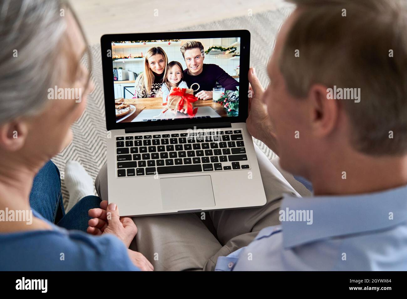 Grandparents video calling family with grandkid on laptop screen. Stock Photo