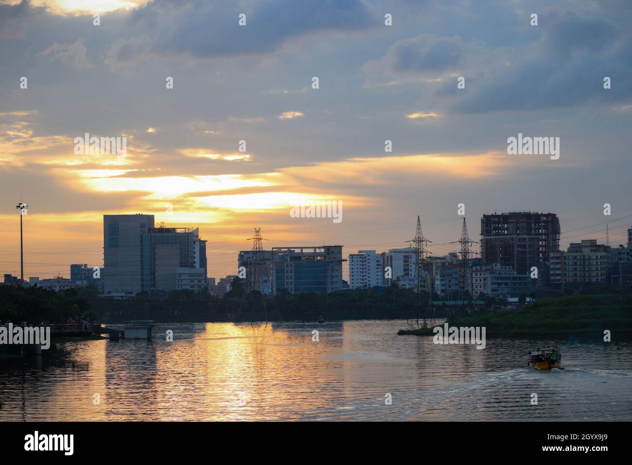 Lake view of Dhaka city with skyline buildings in the evening. Sunlight reflected in the lake water. Stock Photo