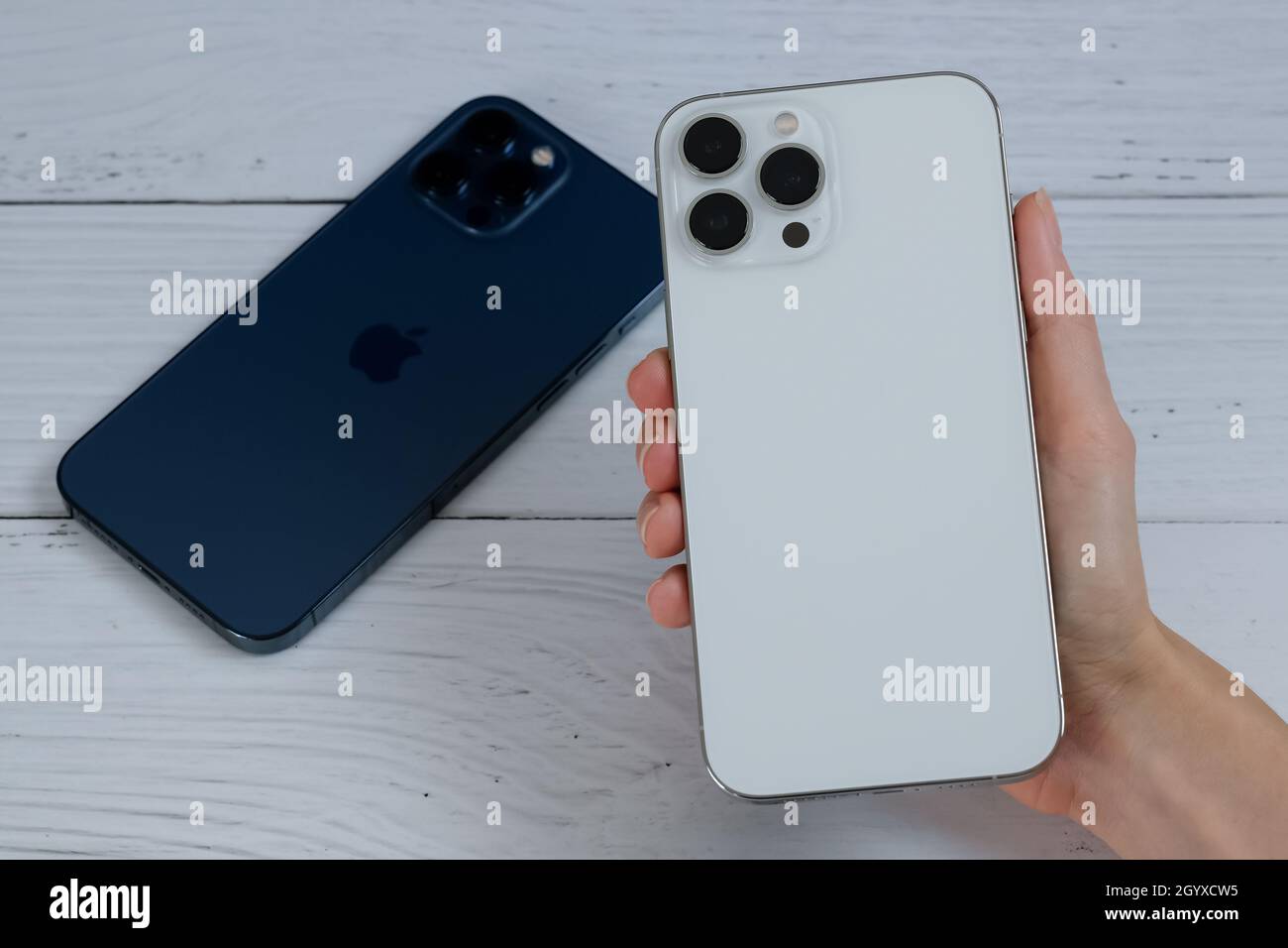 iPhone 13 Pro Max in Silver and iPhone 12 Pro Max in Pacific Blue Stock Photo