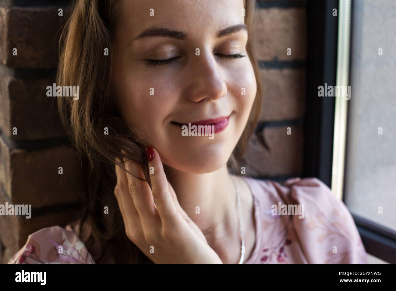 Beautiful young woman in pink dress sits on the windowsill Stock Photo ...