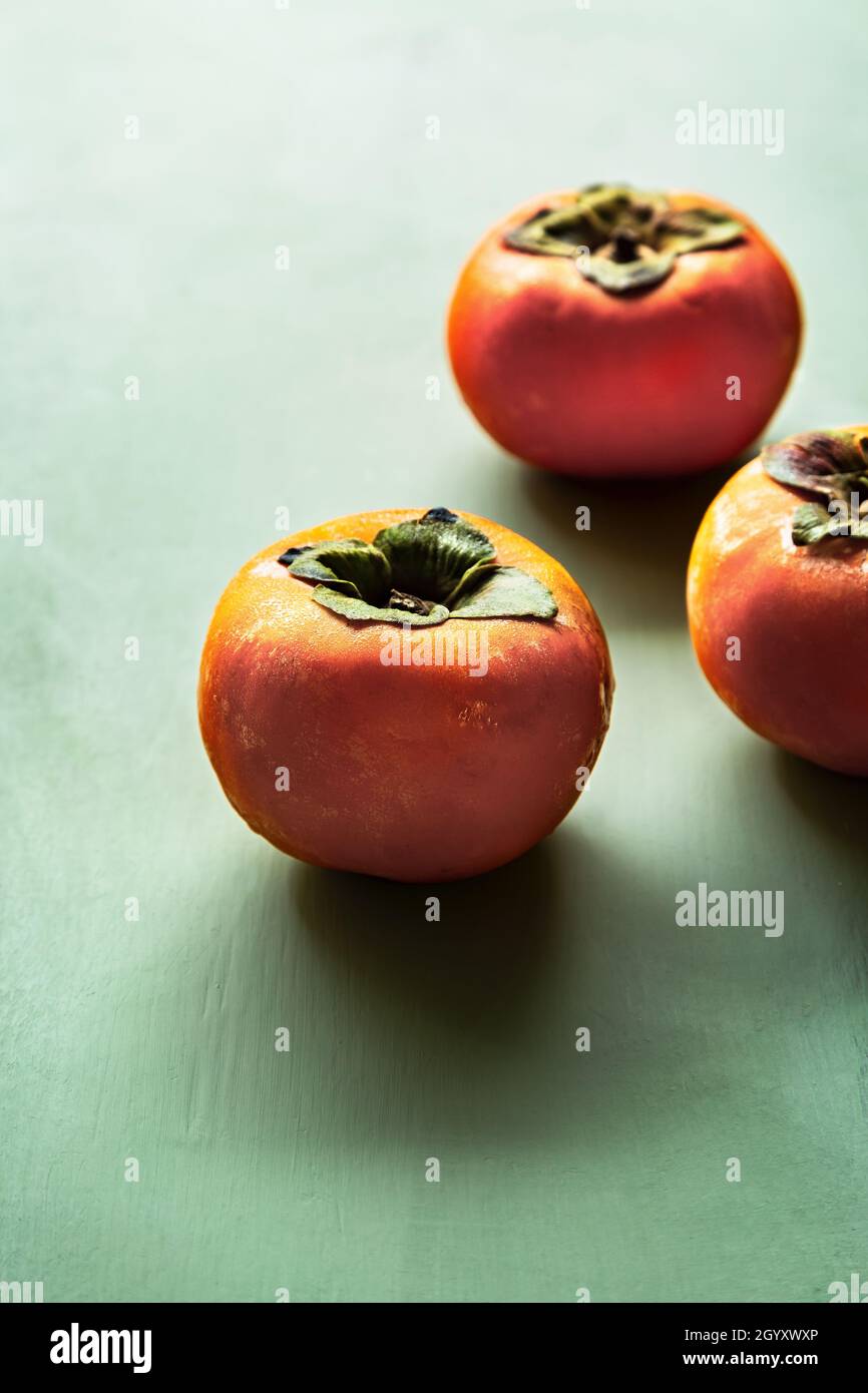 Fresh Persimmons  on green woodboard Stock Photo