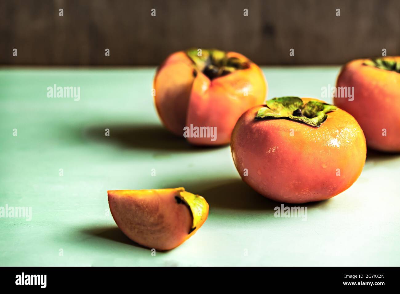 Fresh Persimmons  on green woodboard Stock Photo