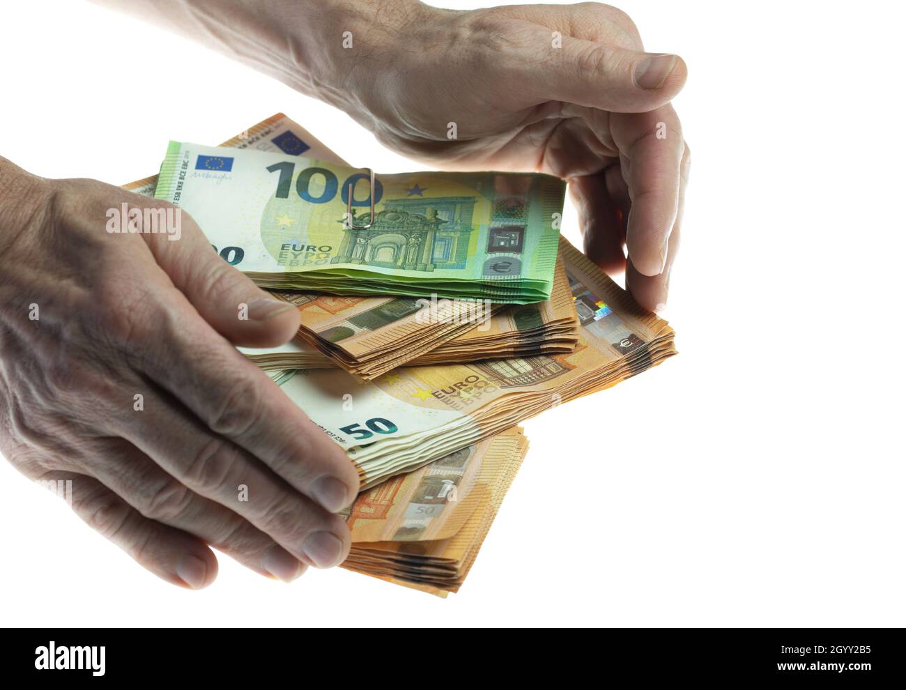 Hands reaching for a stack of euro notes Stock Photo