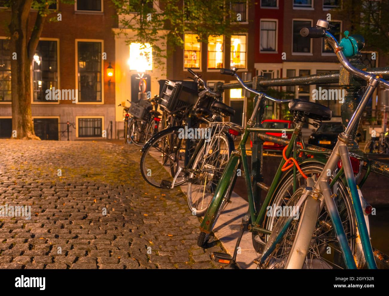 Netherlands. Night Amsterdam. Several bicycles are parked at the canal fence on the cobbled pavement Stock Photo