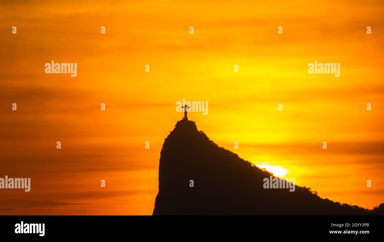 Rio de Janeiro, Brazil - CIRCA 2021: Panorama of Cristo Redentor (Christ the Redeemer) at sunset with orange sky Stock Photo