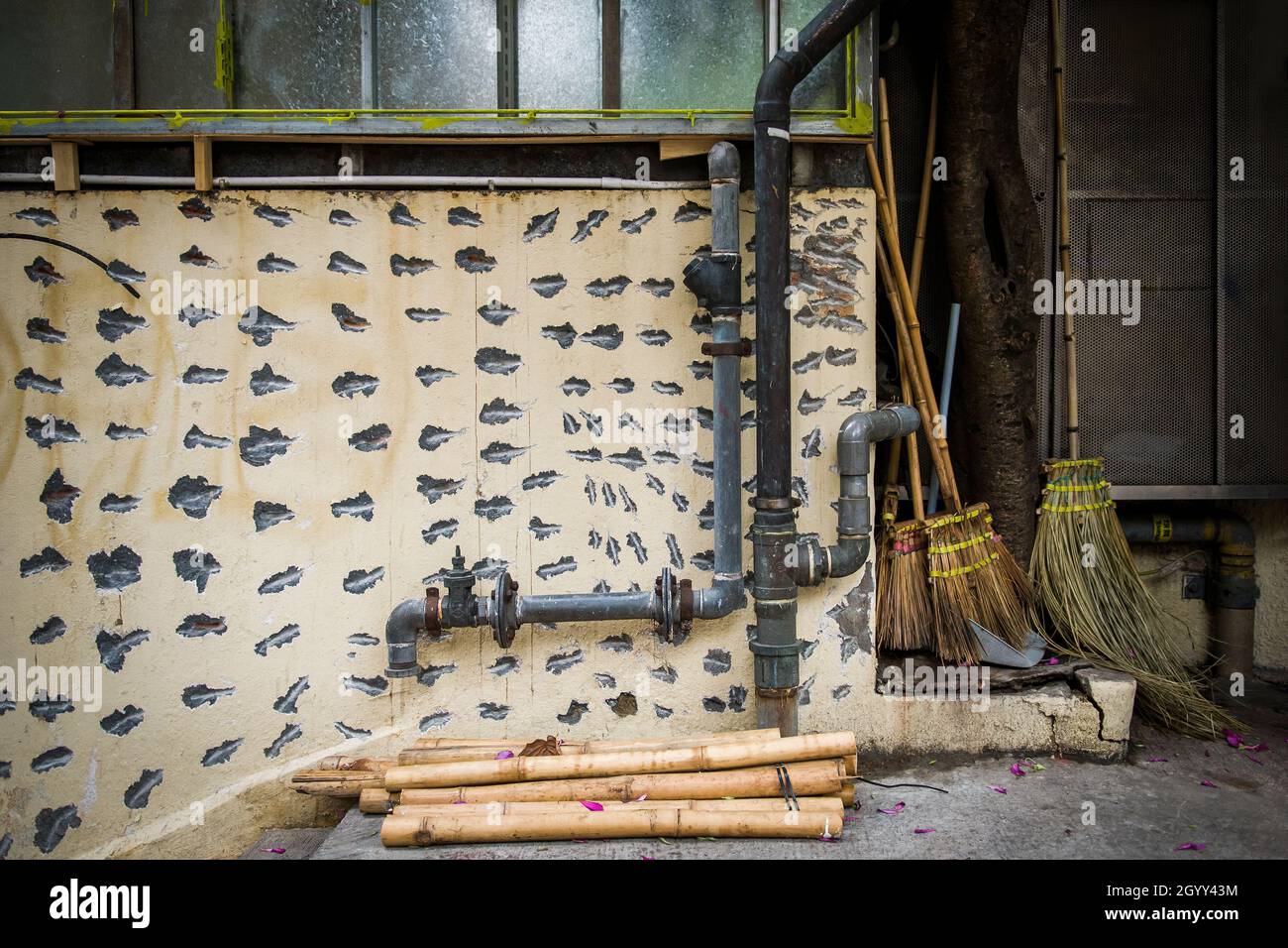 Street scene showing a concrete wall scored prior to re-rendering, downpipes and brooms in Central, Hong Kong Island Stock Photo