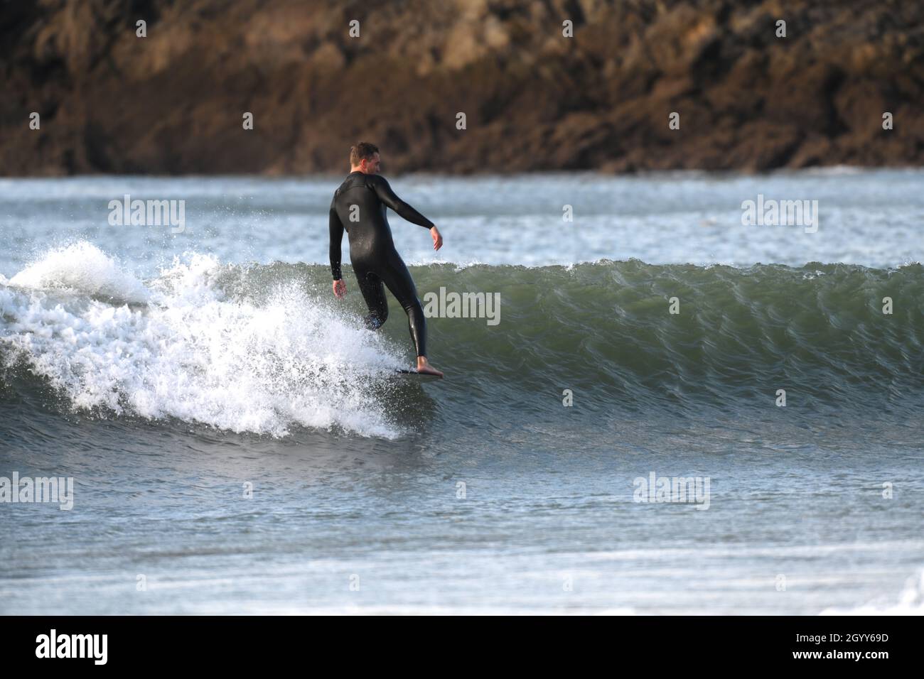 A surfer 'hanging ten' races the breaking wave at Caswell bay on the
