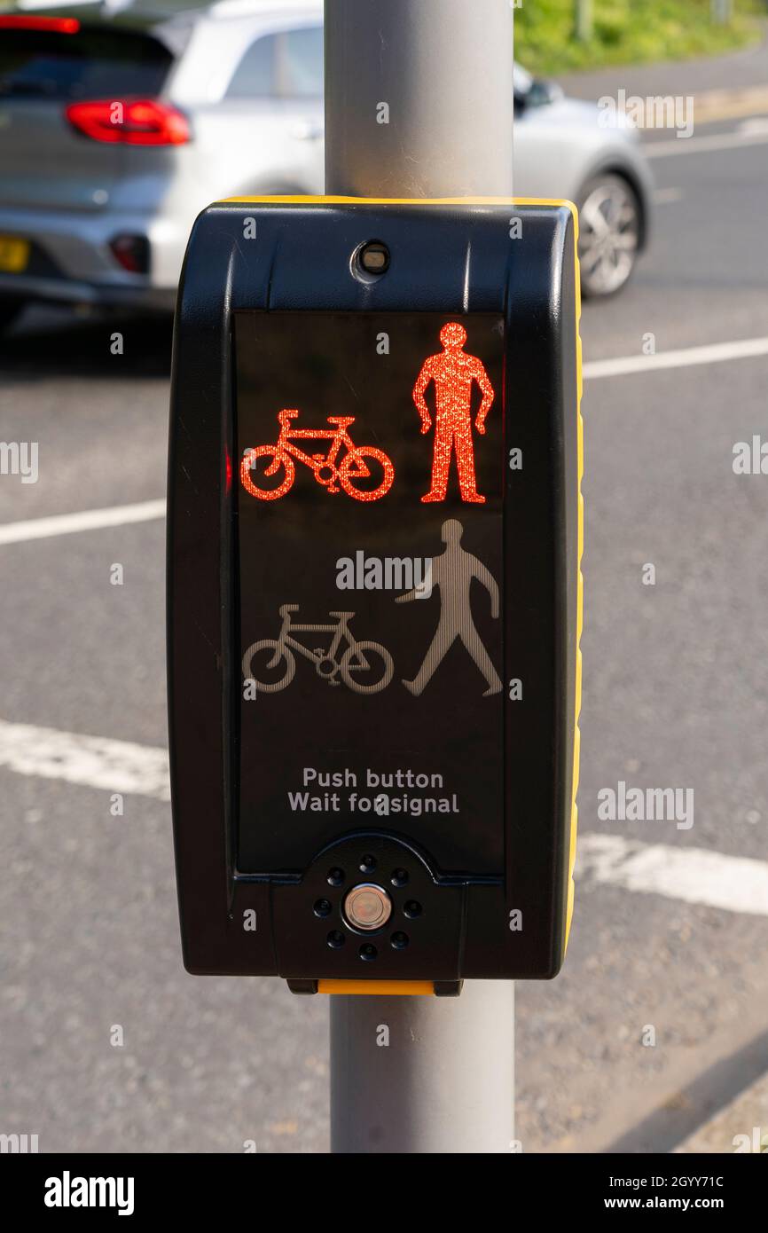 A pedestrian crossing signal on red 'Do Not Cross' next to a busy road with a car crossing in the background in Basingstoke, UK Stock Photo