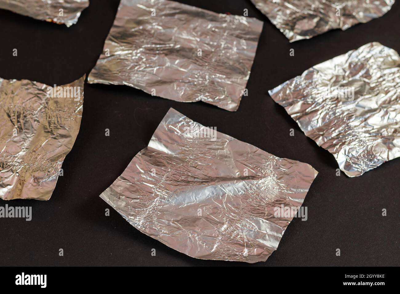 Empty silver candy wrappers on a black background. Crumpled foil from chocolate treats